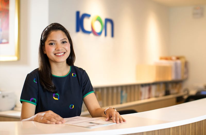 Icon professional smiling to camera behind our reception desk